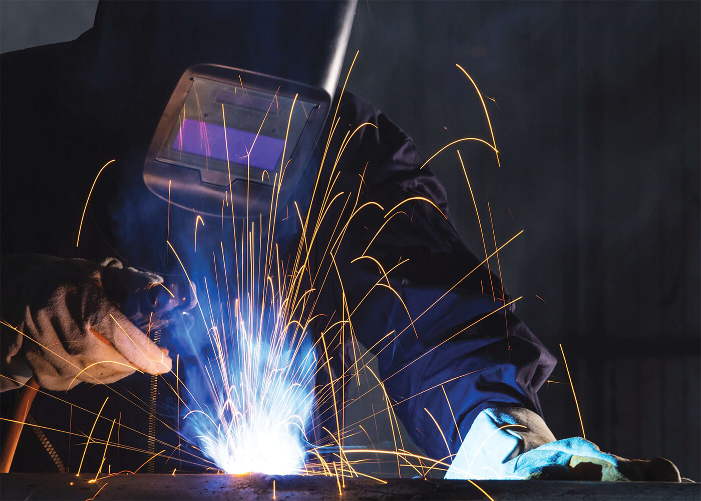 Permian Basin Workforce Welder in protective gear working with bright sparks during skills training