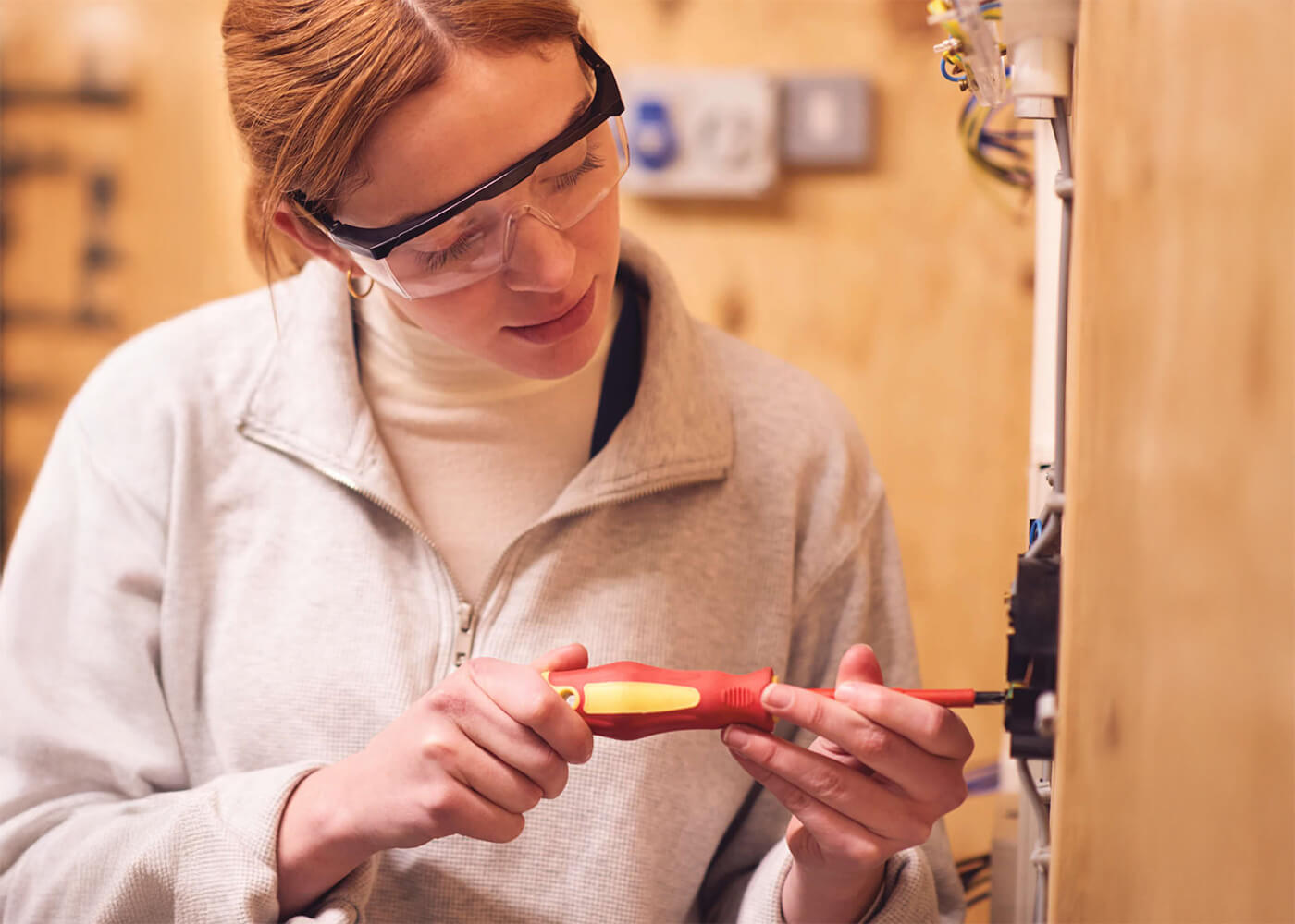Woman in technical training using a screwdriver on electrical equipment